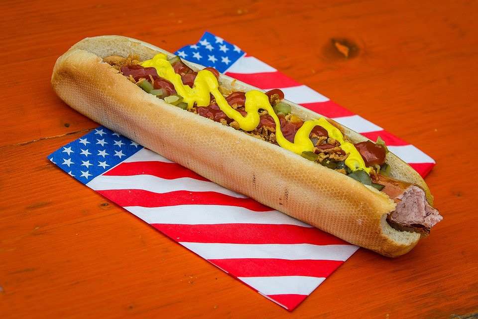 A hot dog sits on top of a napkin printed with an American flag pattern.