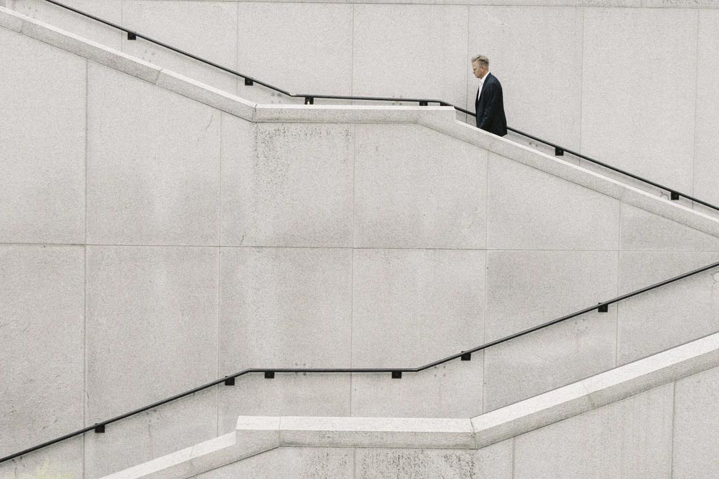 A business professional getting some workday exercise by walking up several flights of stairs outside of an office building.